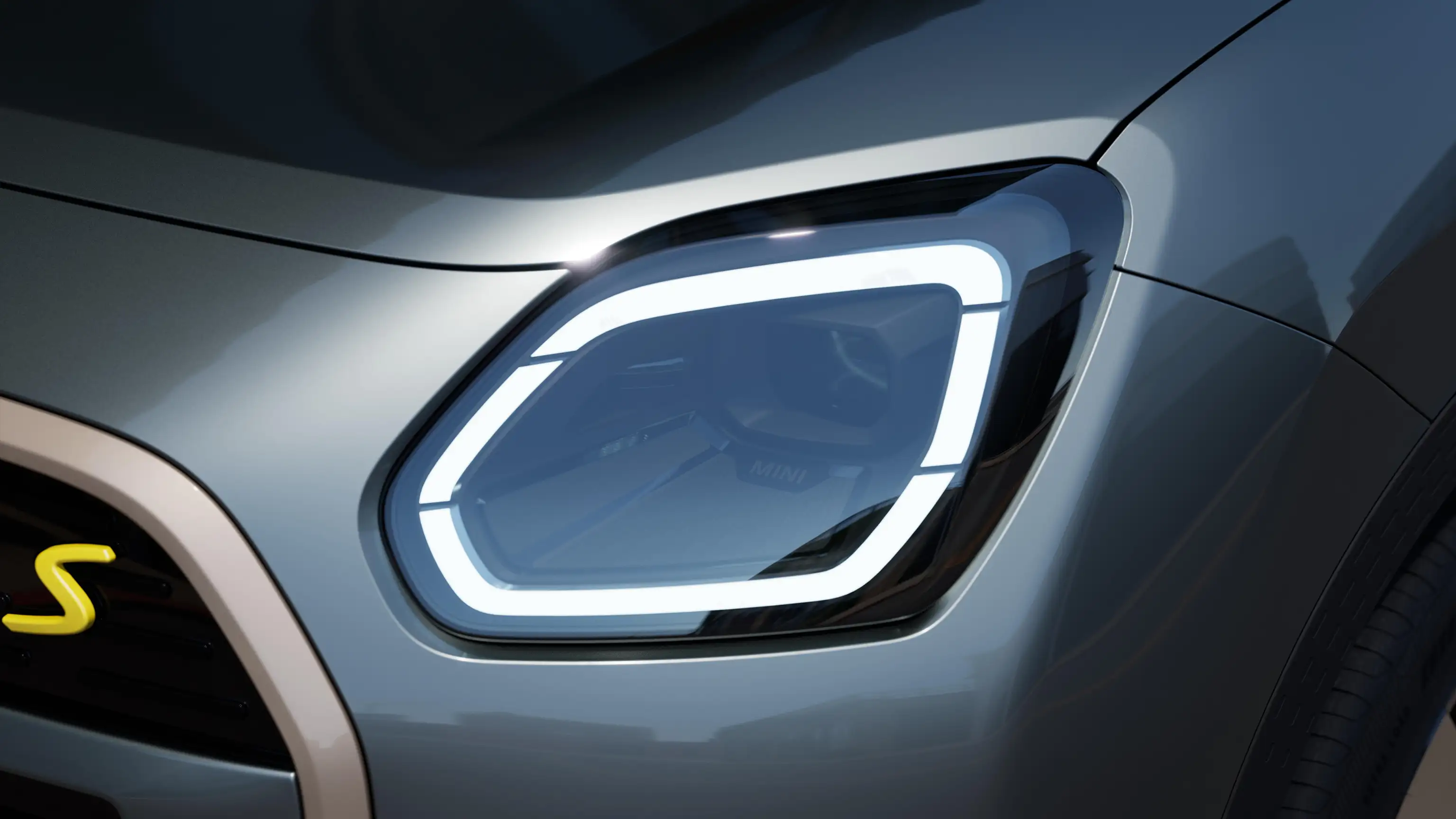 Detail view of the all-electric MINI Countryman headlight with white light on
