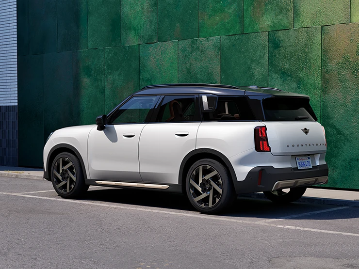 Side rear view of the MINI Countryman in Nanuq White with Black Roof standing on a street.